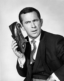 Agent Maxwell Smart using a shoe phone